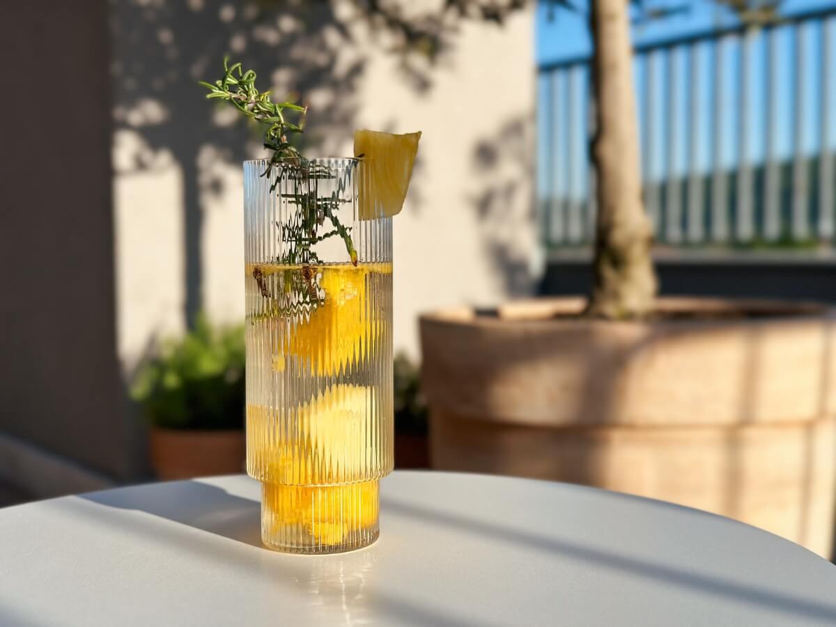 Ananásová limonáda v pohári ozdobená vetvičkou rozmarínu.