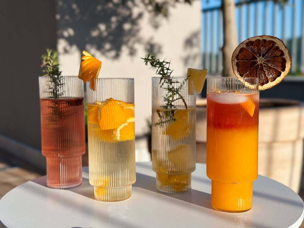 Rôzne druhy koktailov vo vysokých sklenených pohároch ozdobených ovocím.