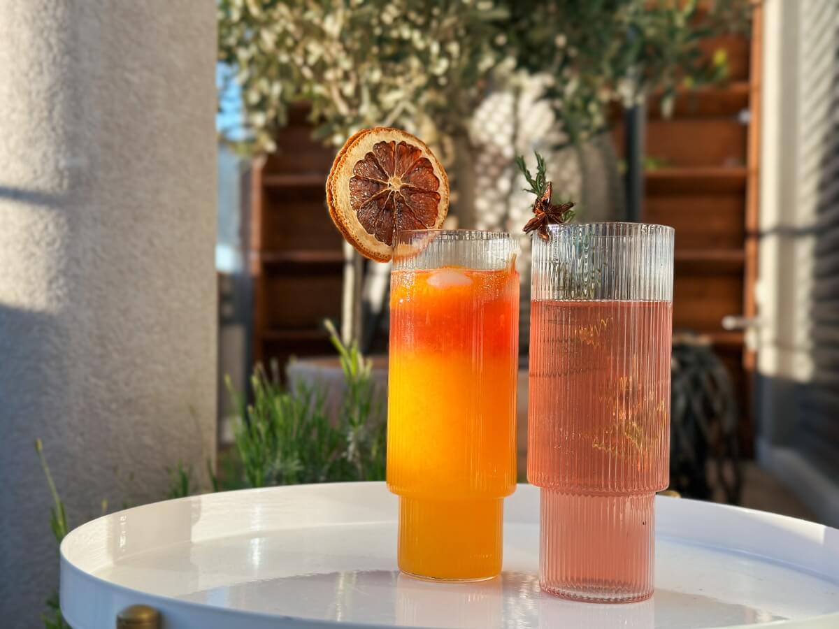 Dva dizajnové sklenené poháre s rôznofarebnými limonádami.