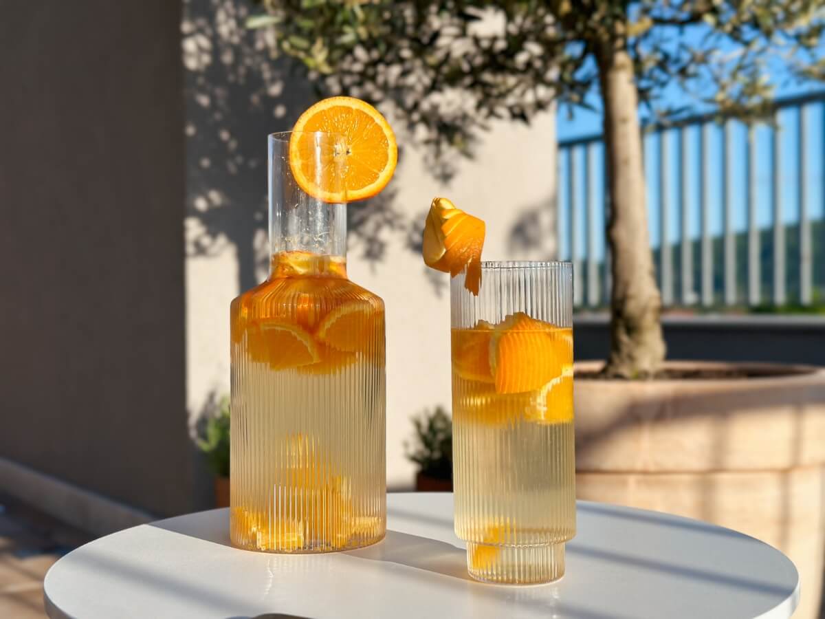 Pomarančová limonáda v dizajnovej karafe a pohári.