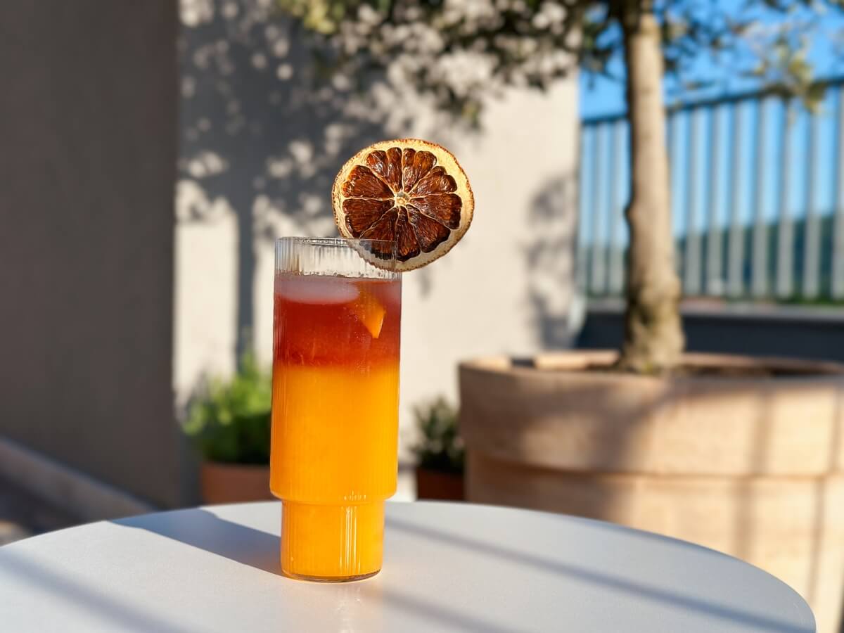 Koktail Tequila Sunrise ozdobený sušeným plátkom pomaranča.