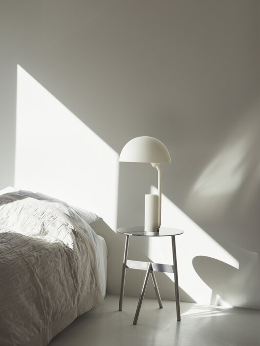 Dizajnová biela stolová lampa na nočnom stolíku v spálni