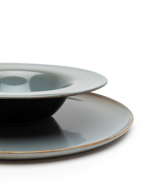 Detail na malý tmavomodrý tanier na cestoviny so sivomodrým vnútrom položený na plytkom sivomodrom tanieri