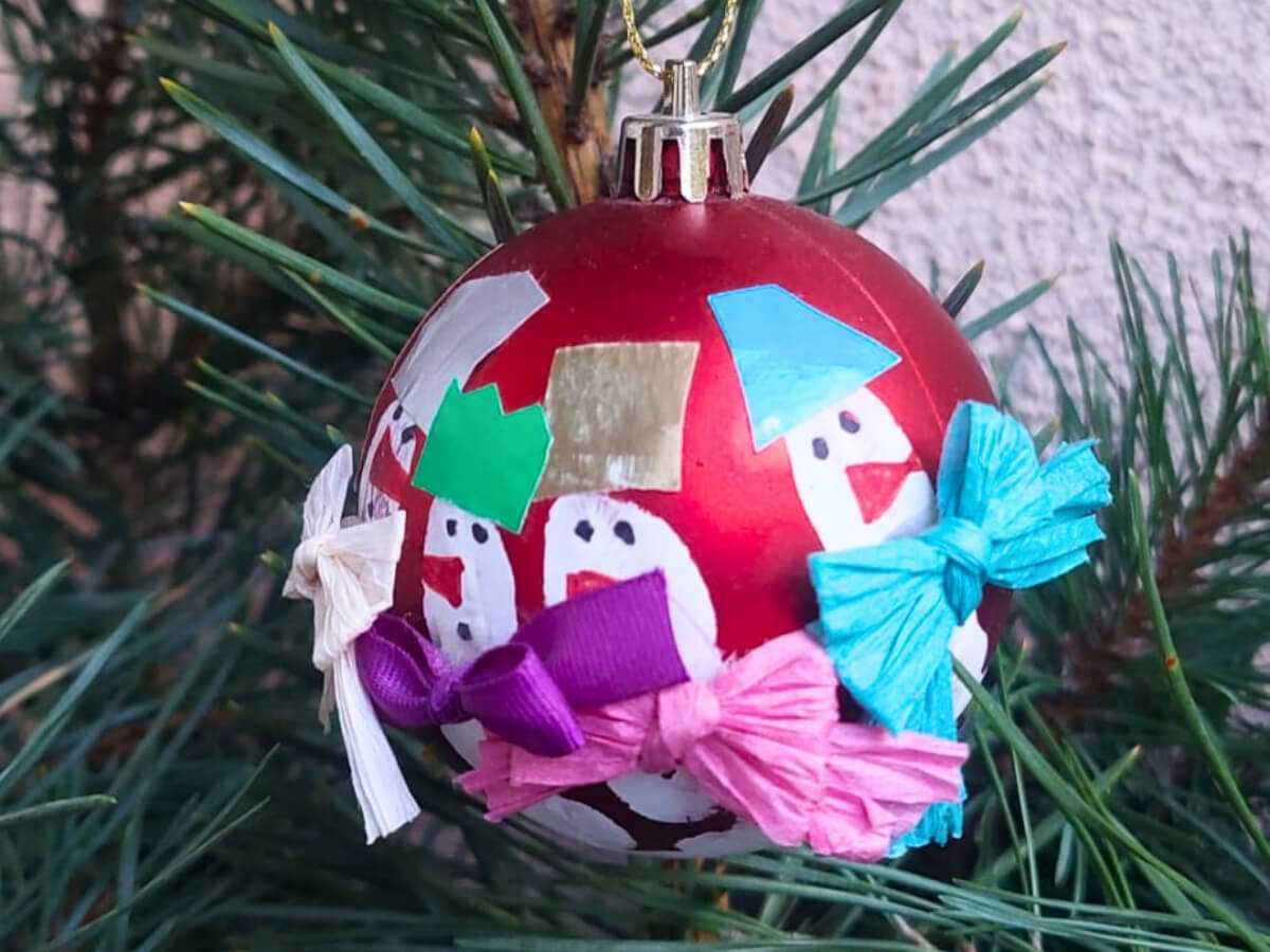 Červená vianočná guľa so snehuliakmi.