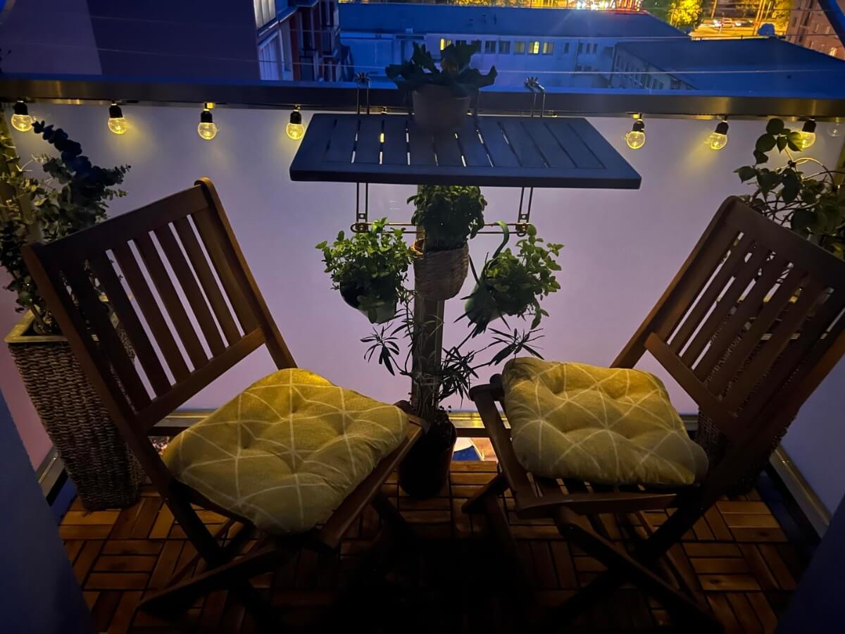 Útulné osvetlenie malého balkóna prostredníctvom reťaze žiaroviek.