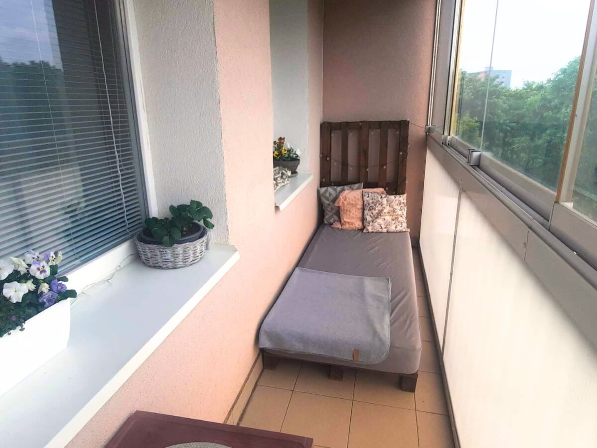 Posteľ z paliet na malom úzkom balkóne.