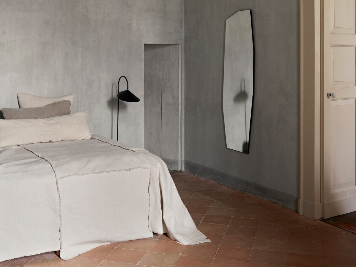 Ustlaná posteľ s dekoračnými vankúšmi v minimalistickej spálni.