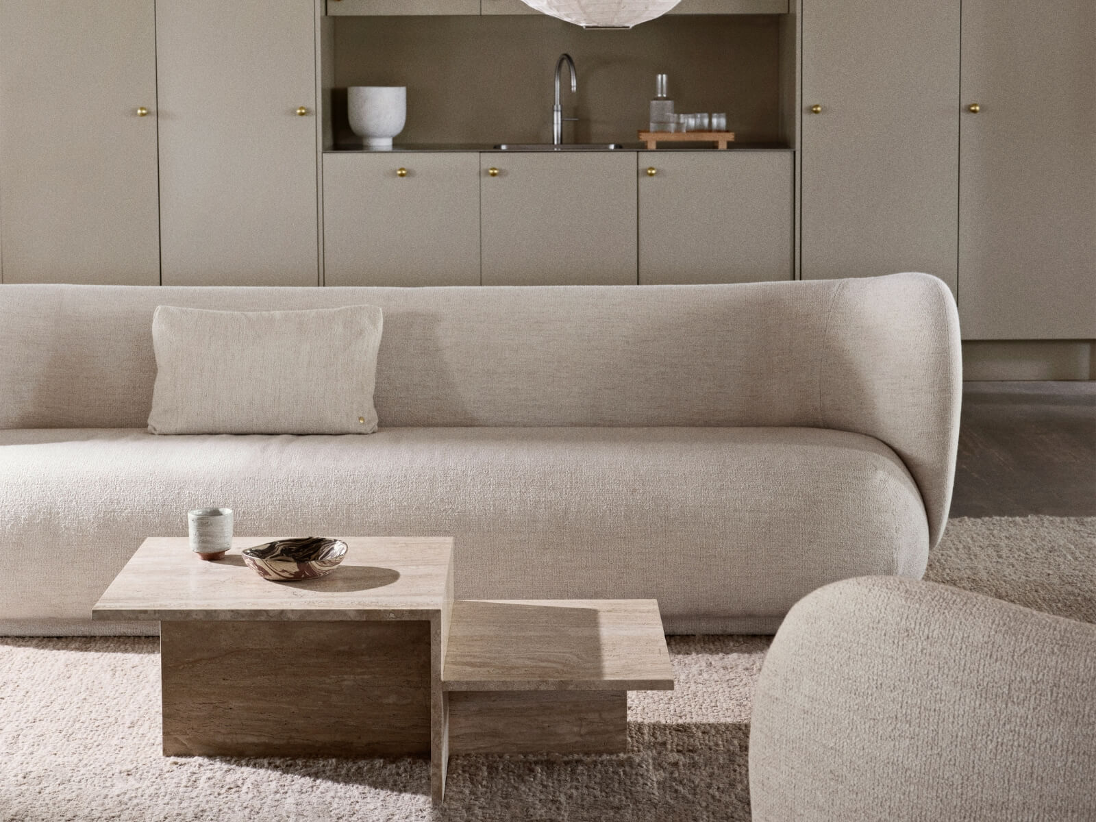 Dizajnová dlhá bledá sedačka v modernej obývačke s kuchyňou.