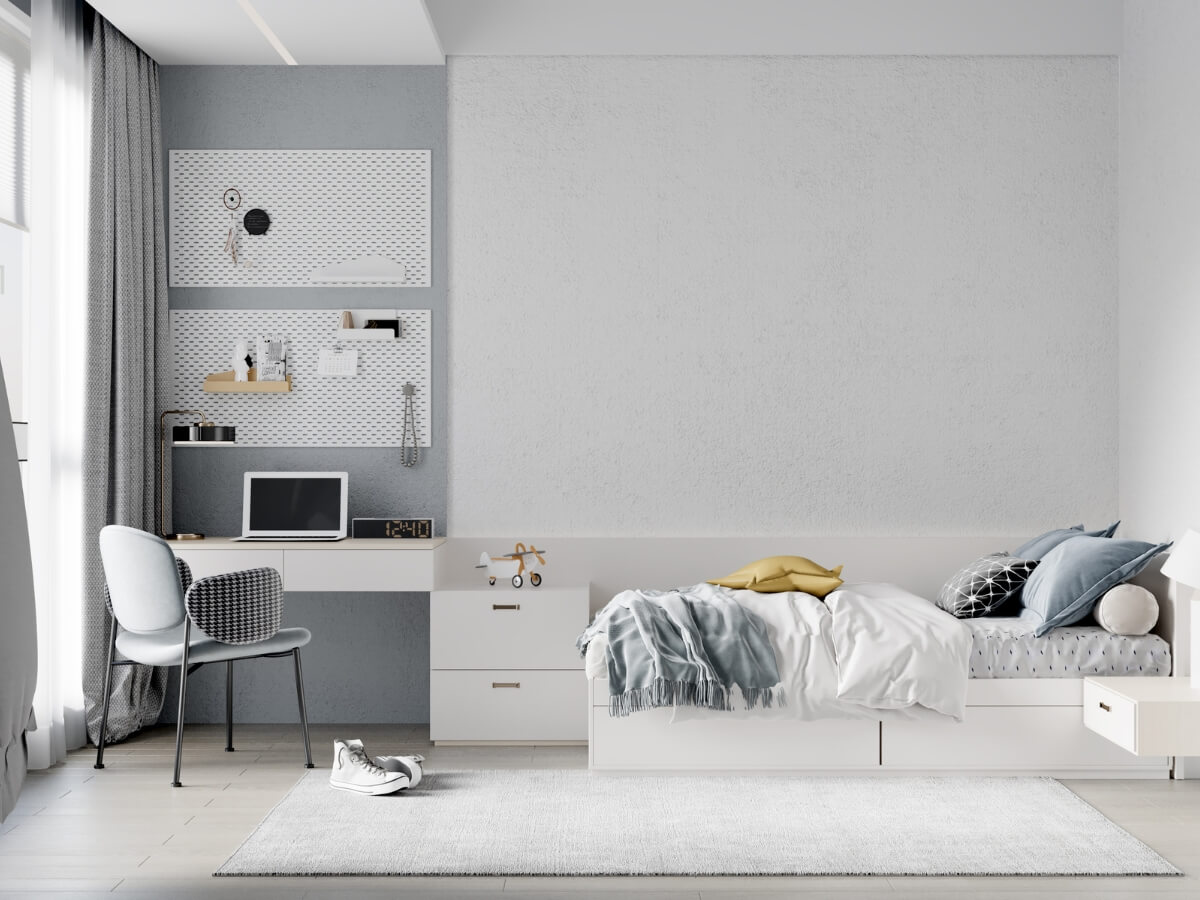 Písací stôl a posteľ v minimalistickej detskej izbe v šedých odtieňoch.