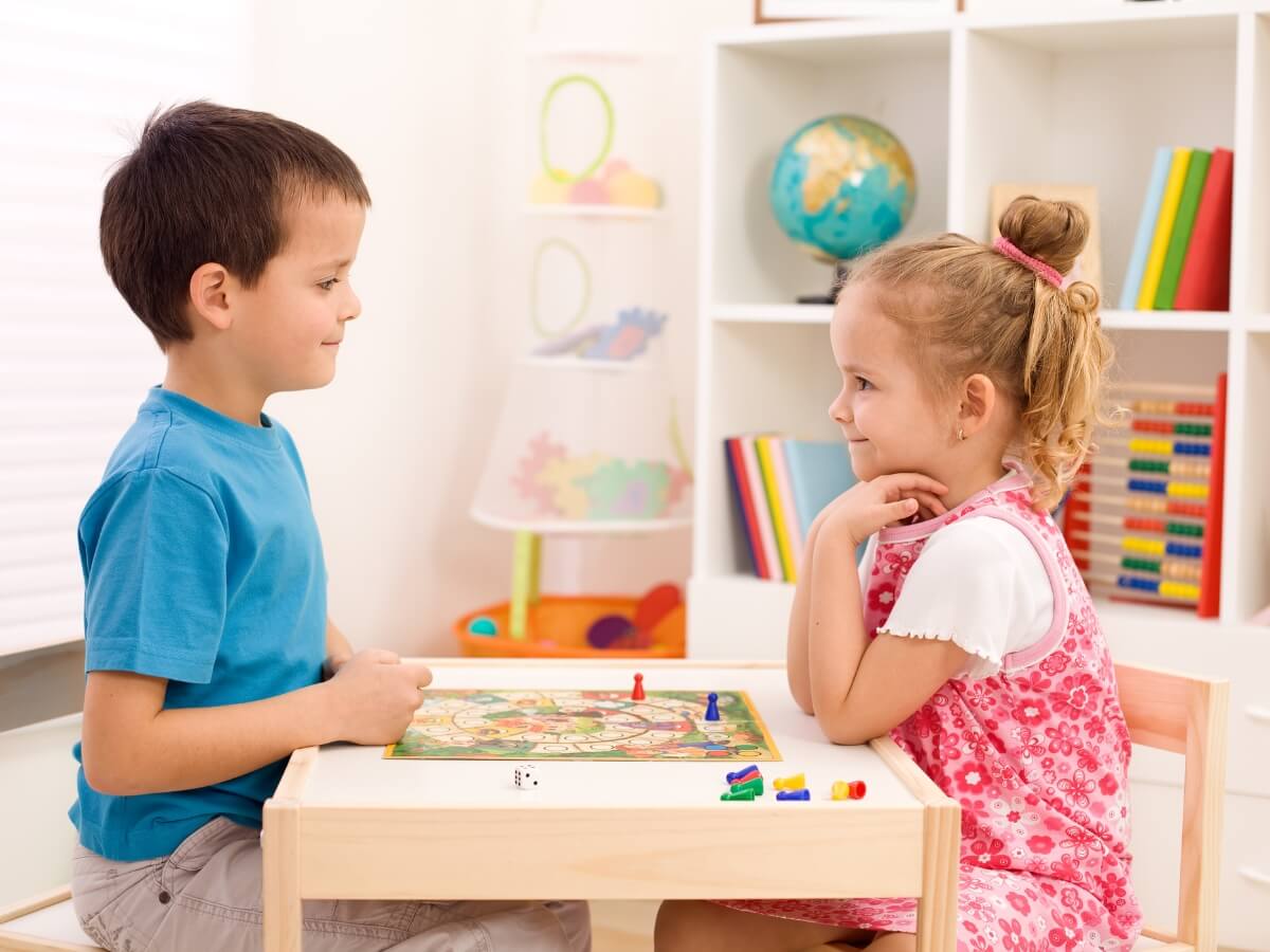 Dve malé deti pri spoločenskej hre v detskej izbe.
