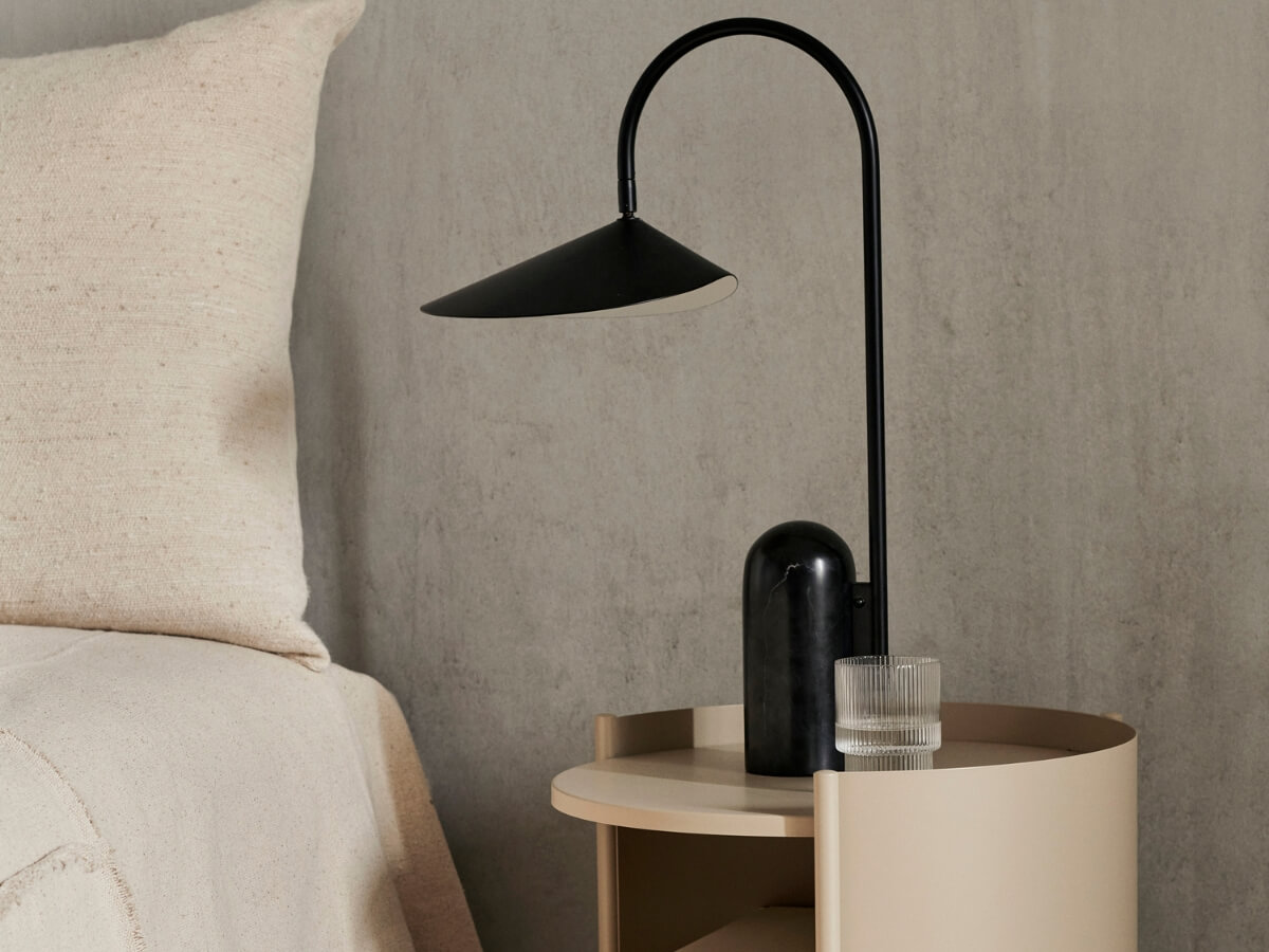 Dizajnový nočný stolík s otvoreným úložným priestorom a štýlovou čiernou lampičkou.