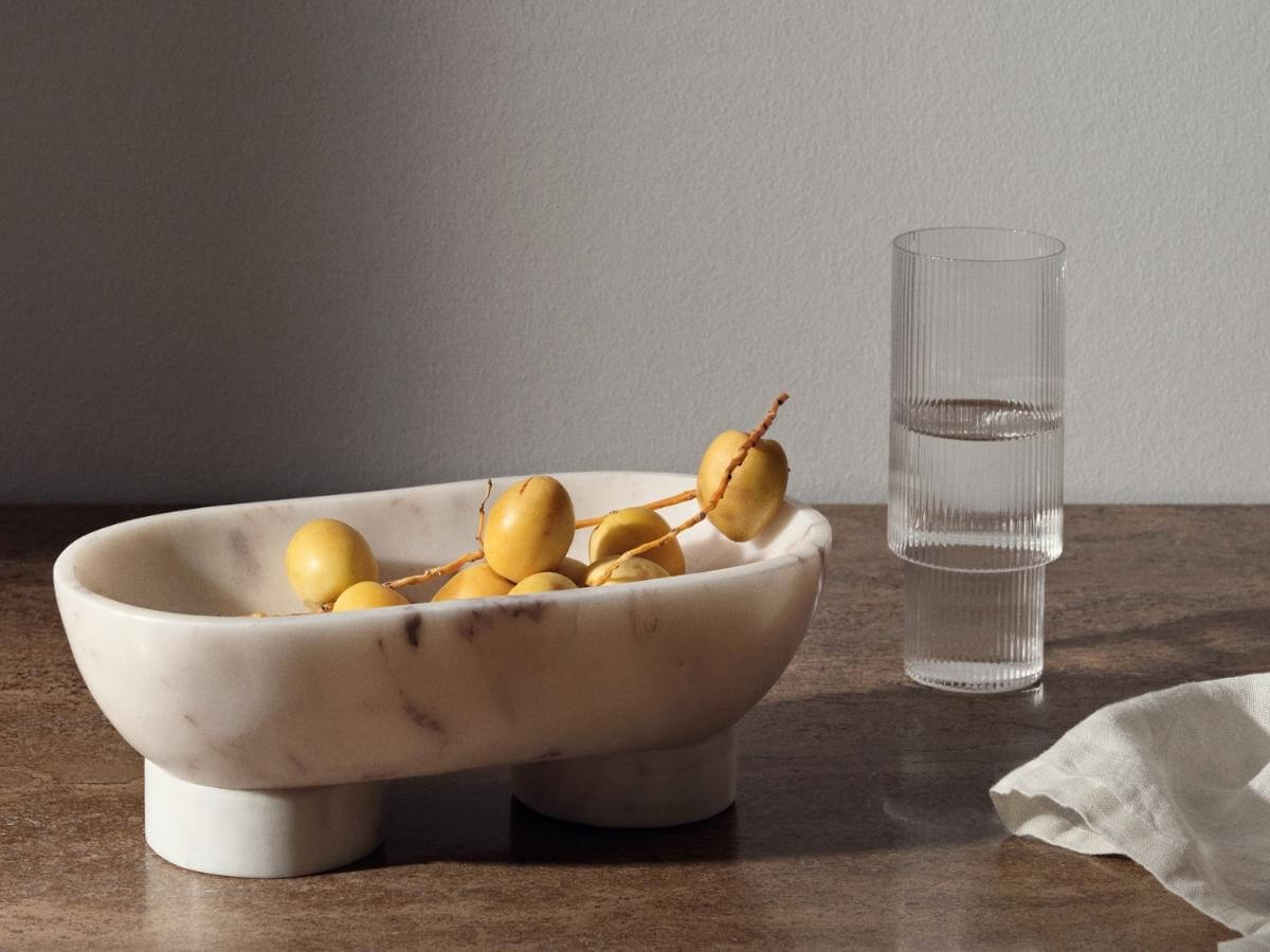 Dizajnová miska s ovocím a pohár vody.
