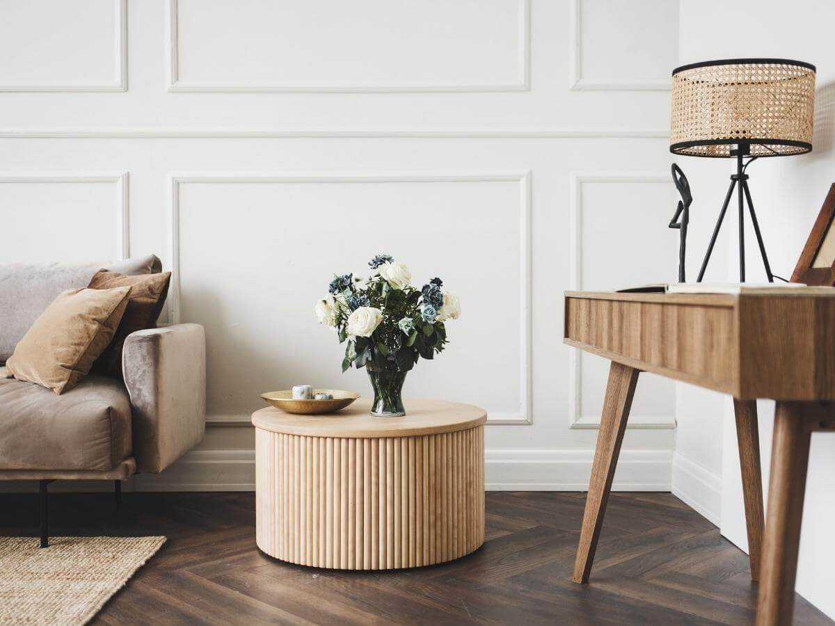Konferenčný drevený stolík s kvetmi v obývačke v škandinávskom interiérovom štýle.