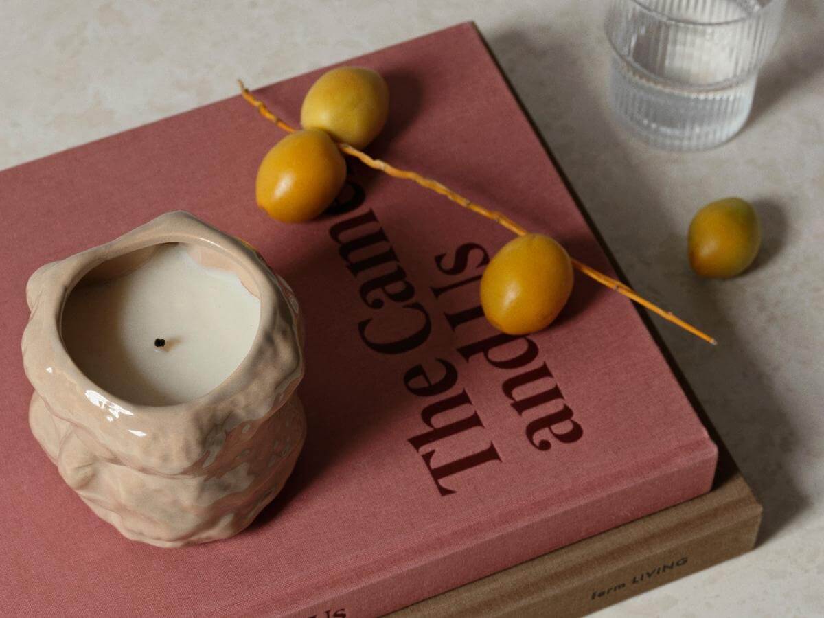 Sviečka v keramike položená na štýlových knihách.