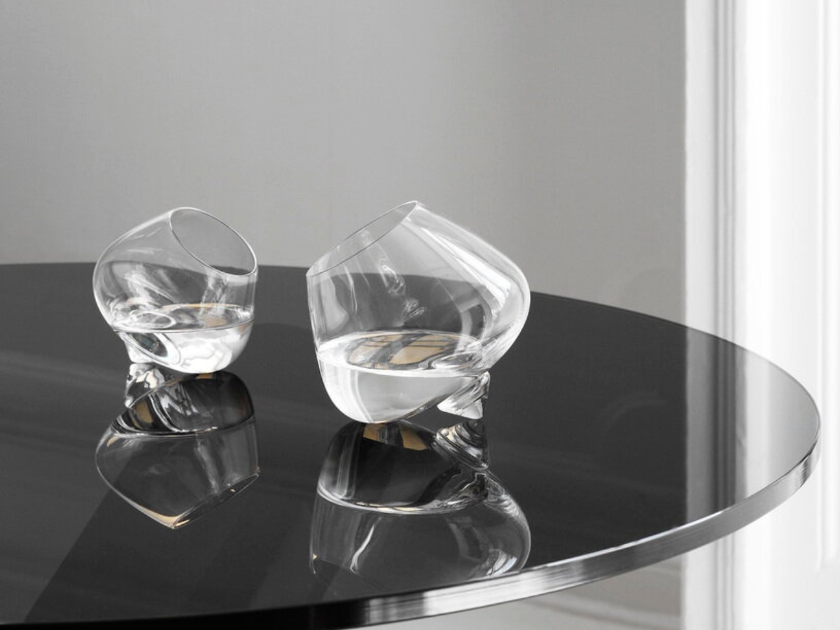 Dva číre poháre na koňak umiestnené na čiernom stolíku.