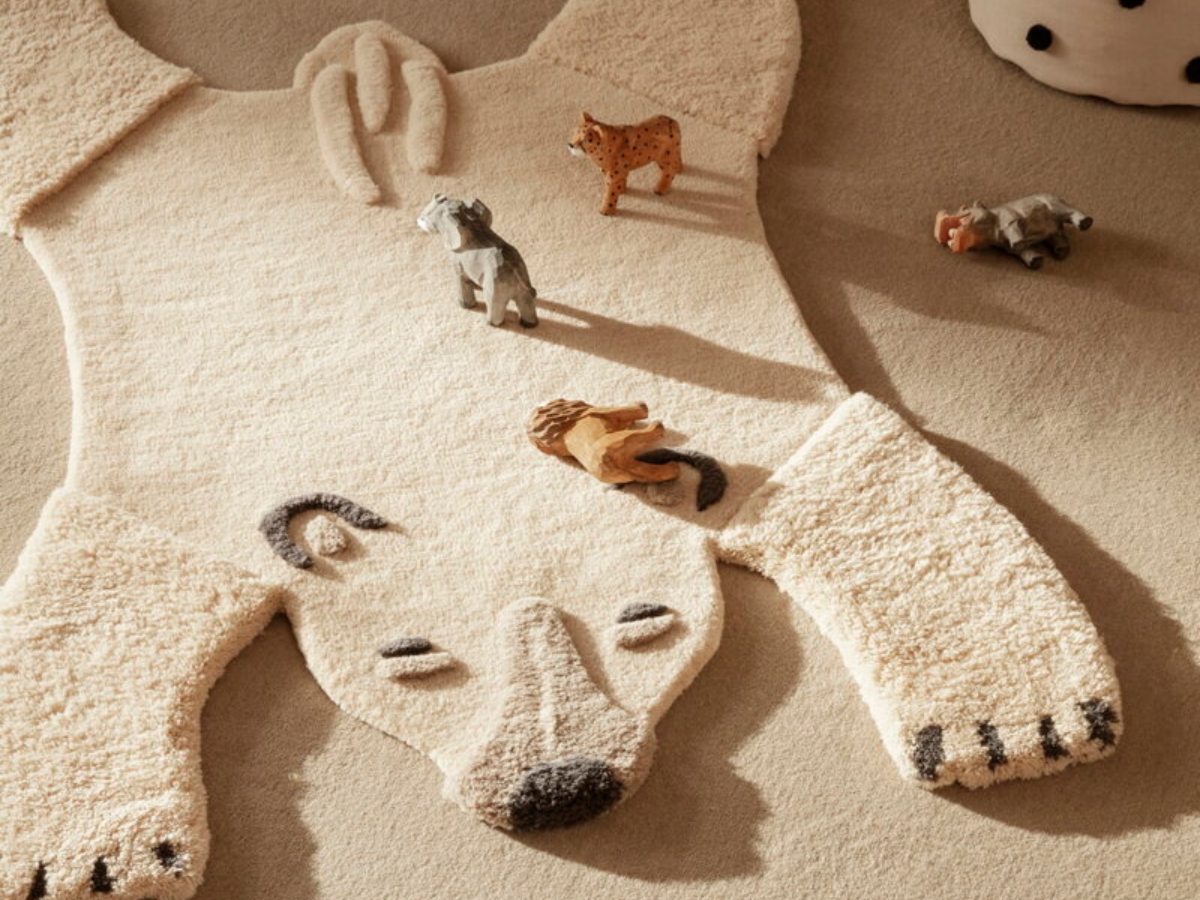 Ručne všívaný koberček v tvare ľadového medveďa, na ktorom sú hračky.