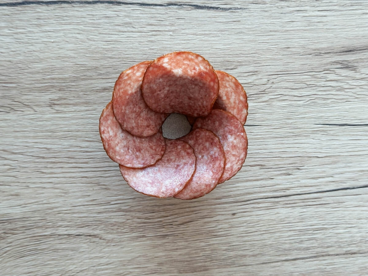 Plátky salámy položené na okrajoch malej misky.
