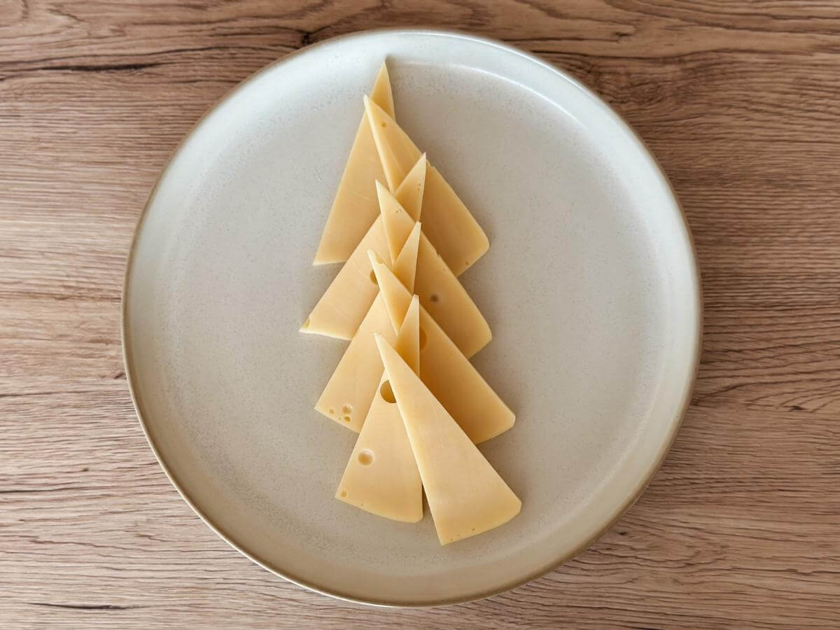 Kúsky syra v tvare trojuholníka naaranžované na tanieri ako stromček.