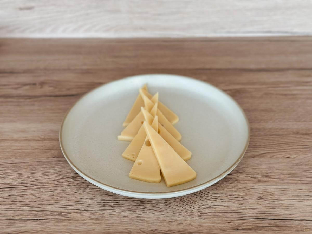 Trojuholníkové kusy syra uložené na tanieri v tvare stromčeka.