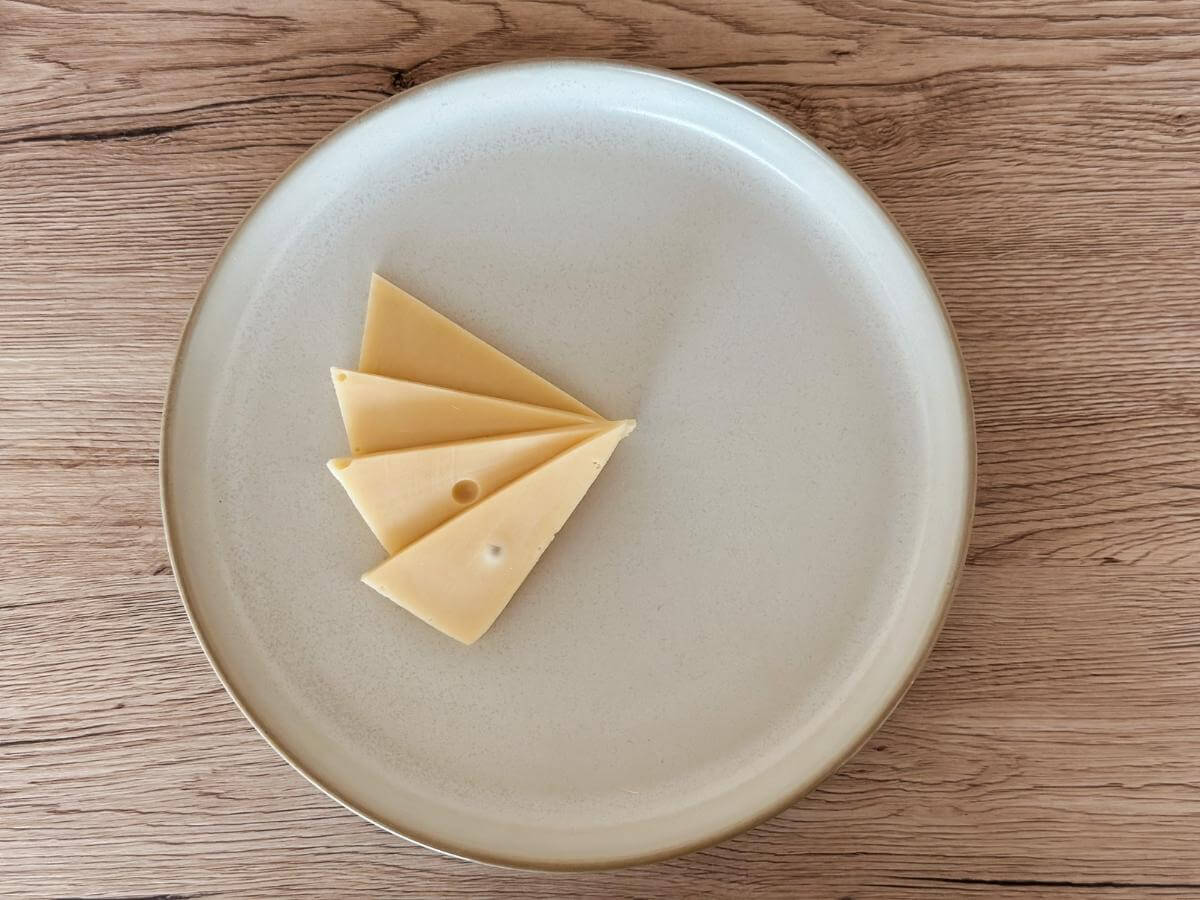 Odkrojený syr v tvare trojuholníka položený na tanieri ako vejár.