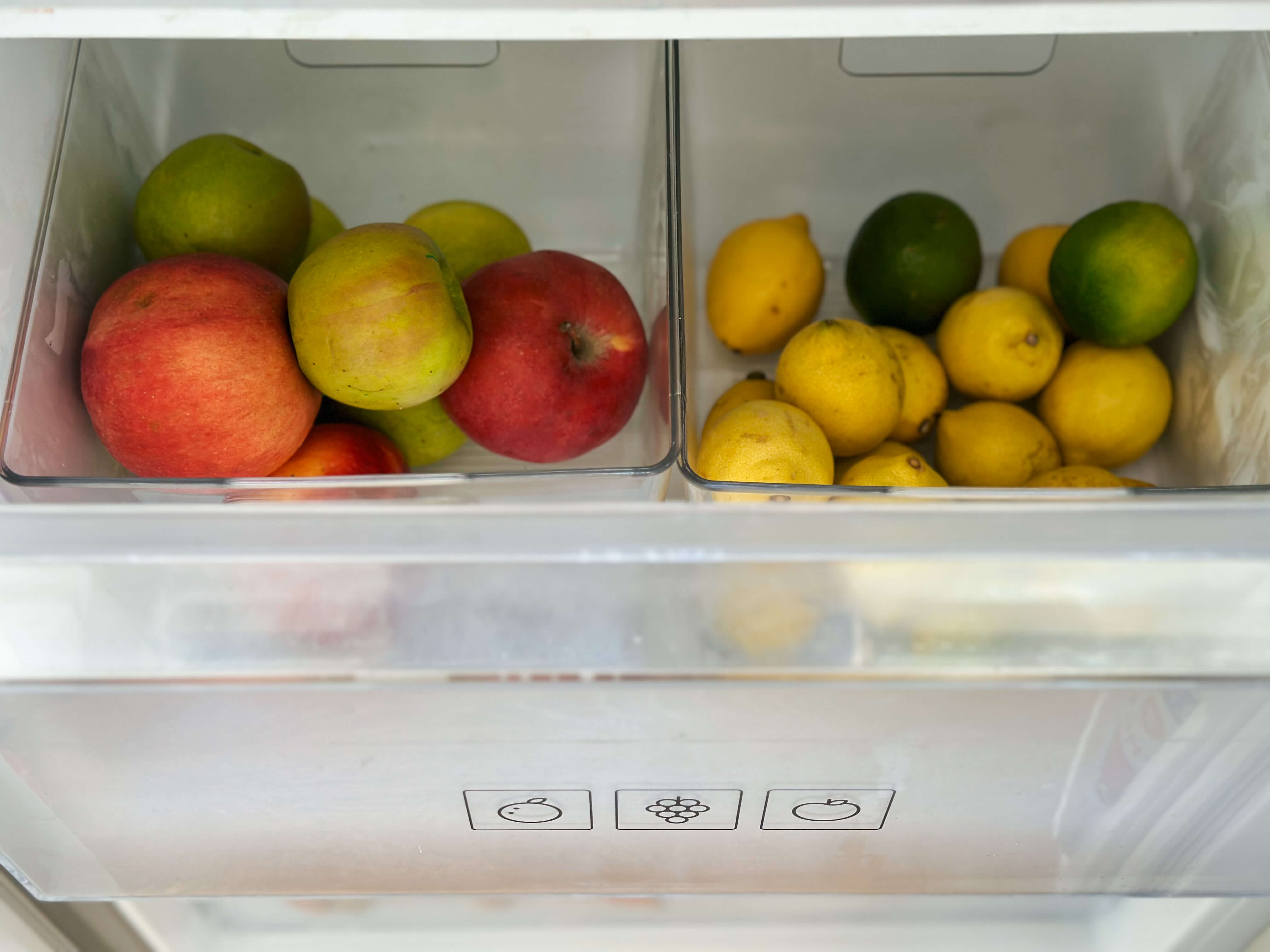 Jablká a citróny v zásuvkách v chladničke.