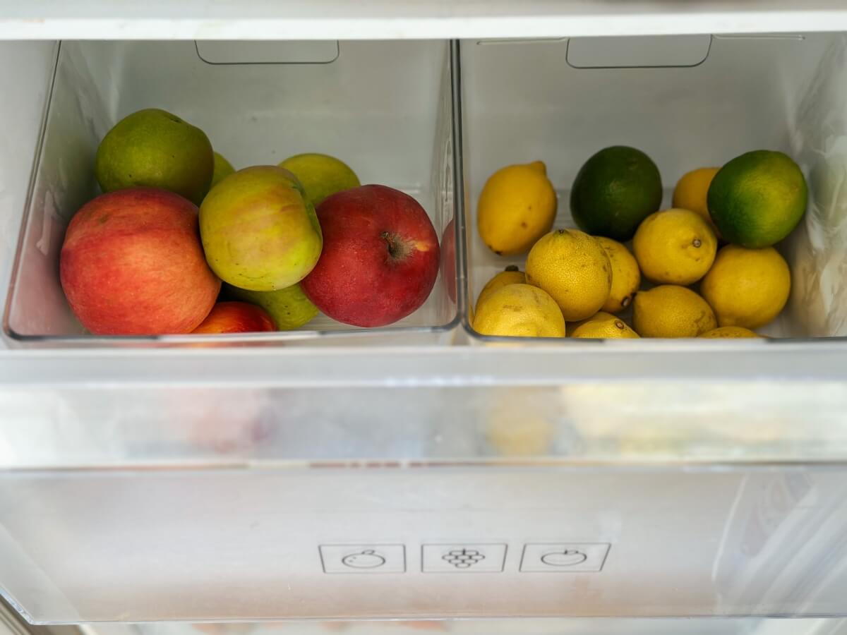 Jablká a citrusy v oddelených zásuvkách v chladničke.