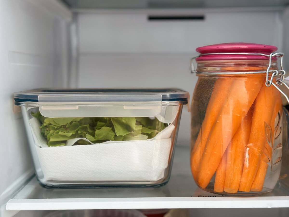 Listový šalát a mrkva uskladnené v sklenených nádobách v chladničke.