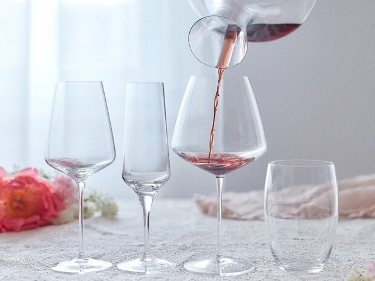 Liatie červeného vína z dekantéru do rôznych pohárov na víno.