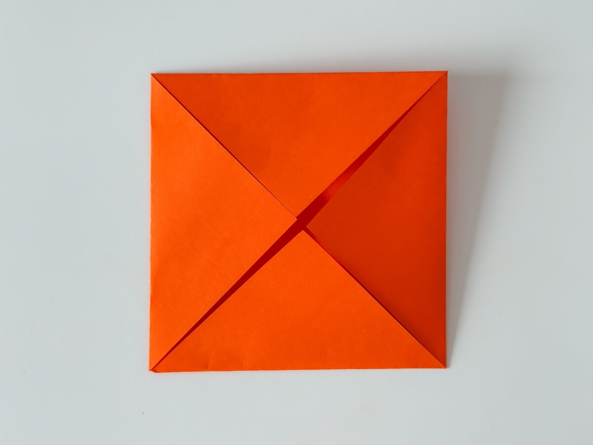 Oranžový origami papier zložený zo štyroch trojuholníkov.