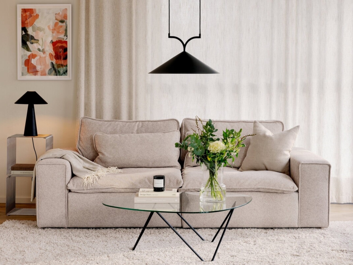 Čierne závesné svietidlo a čierna stolová lampa vo svetlej obývačke.