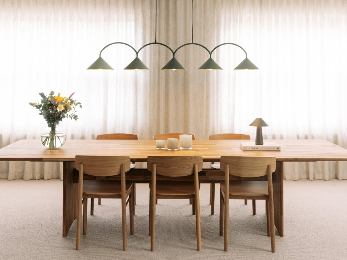 Zelená závesná lampa s piatimi tienidlami v tvare trojuholníka nad jedálenským stolom.