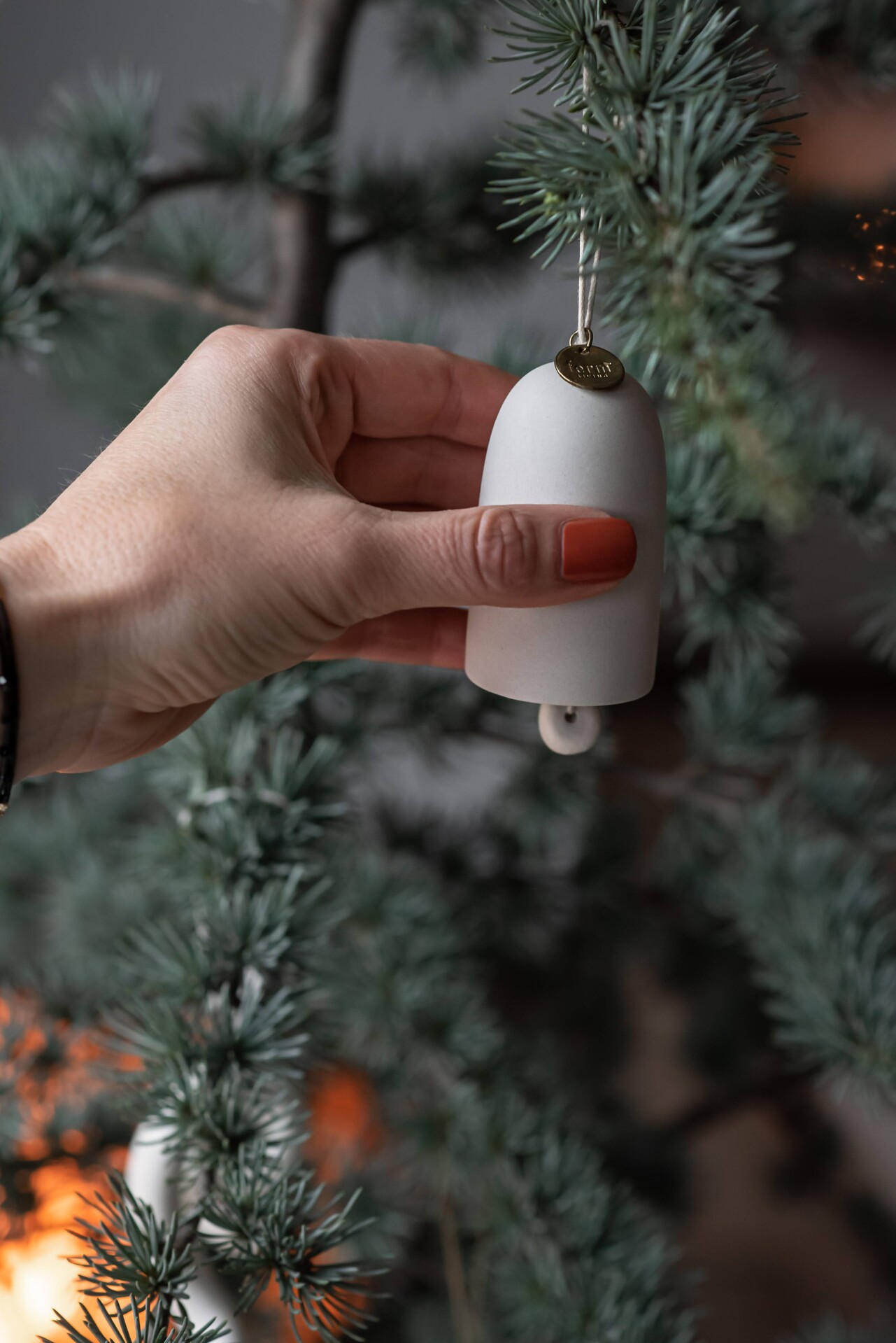 Keramický biely zvonček na vianočnom stromčeku.