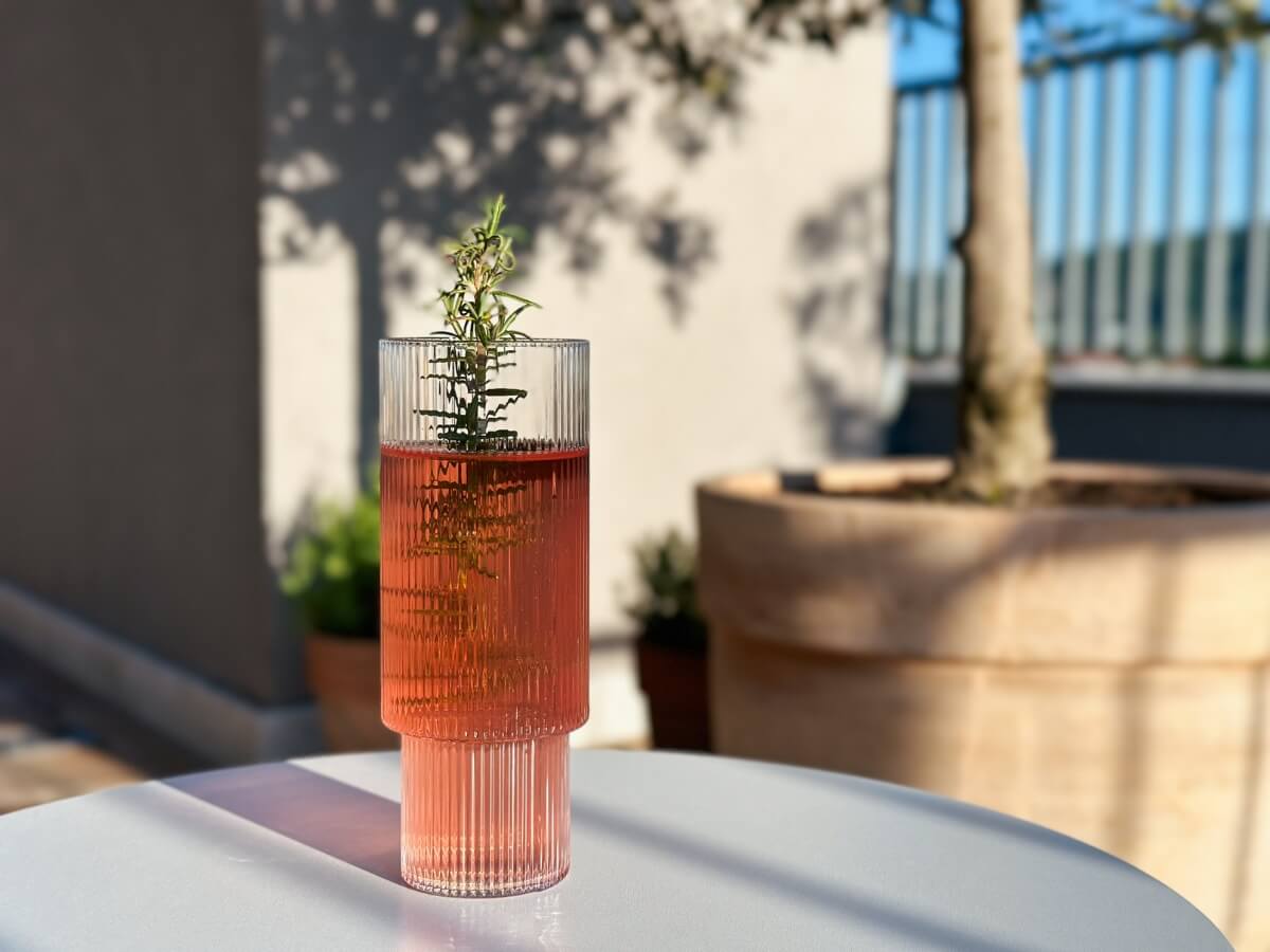 Čerešňová limonáda vo vysokom pohári s vetvičkou rozmarínu.