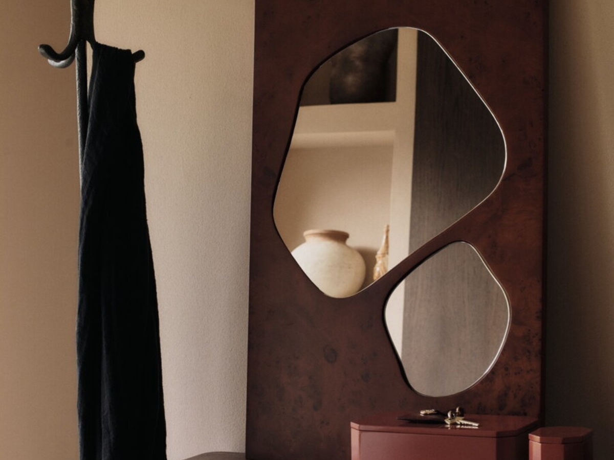 Asymetrické nástenné zrkadlo s rámom z tmavo moreného topoľového dreva v predsieni.