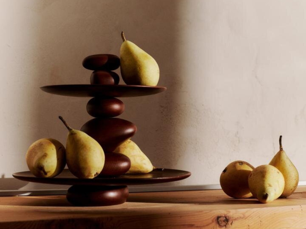 Dizajnový dvojposchodový etažér z bukového dreva tmavohnedej farby, na ktorom sú hrušky.