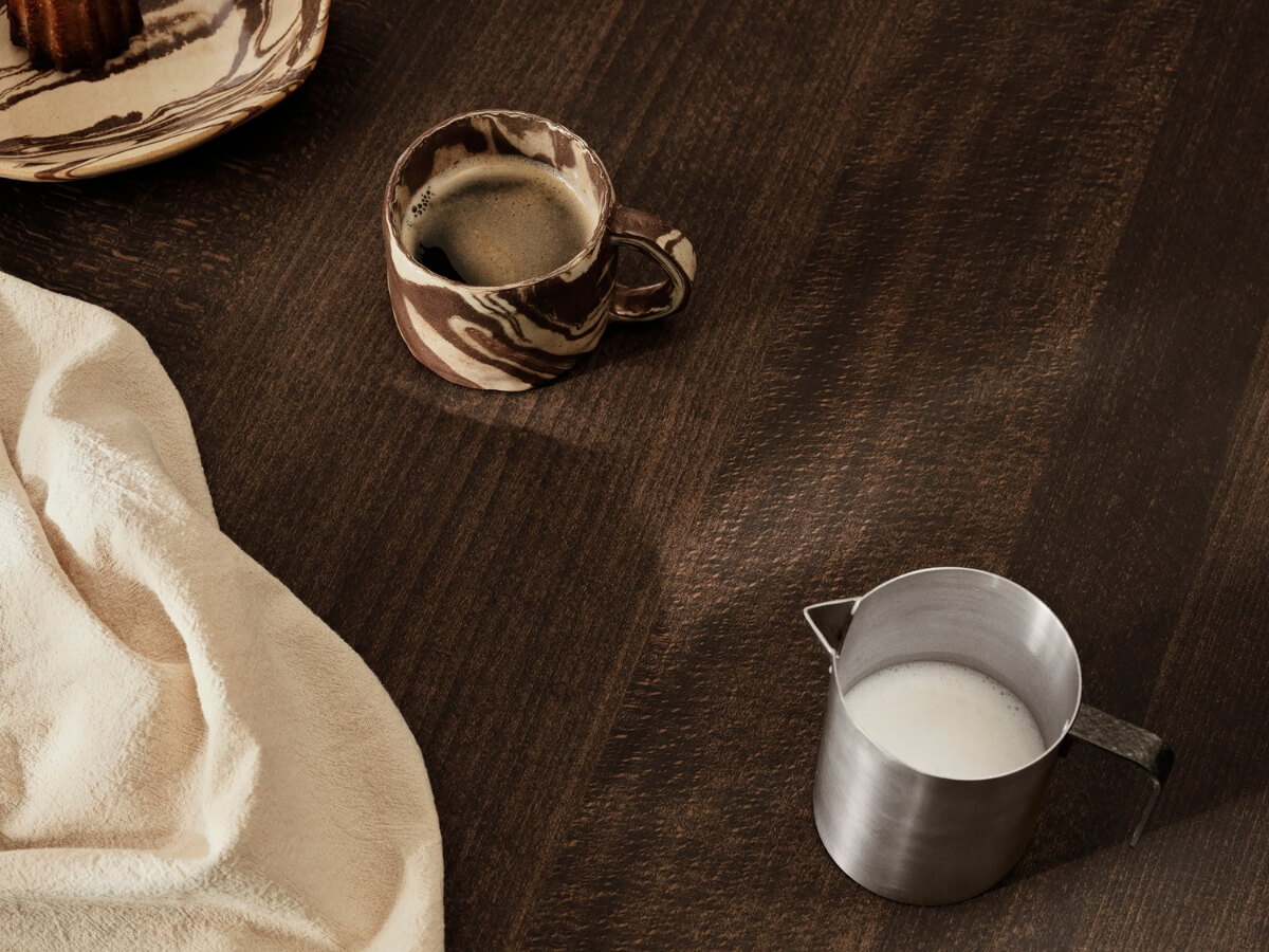 Káva v dizajnovej mramorovej šálke a mlieko v kovovej nádobe.
