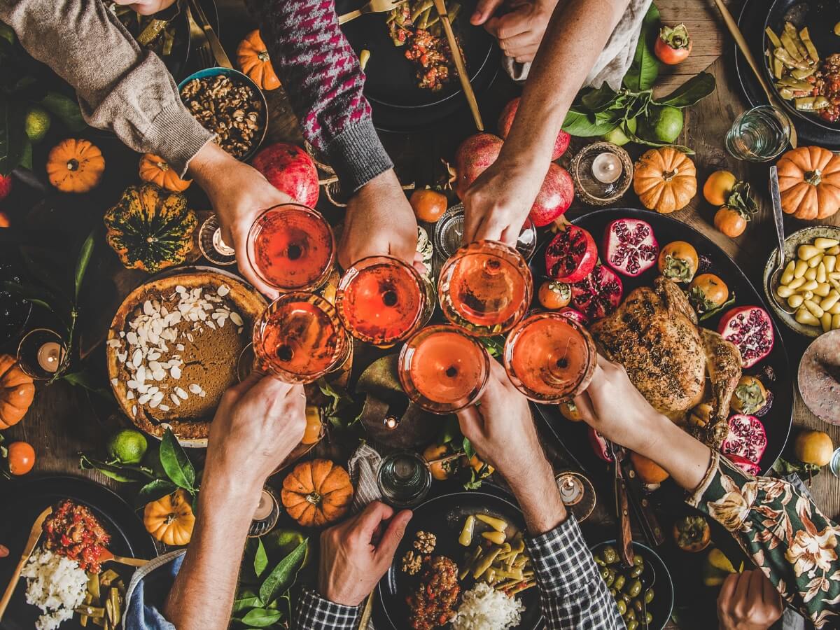 Pripíjanie s ružovým vínom nad prestretým stolom.