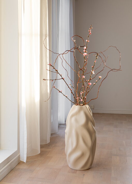 Vysoká keramická váza s vetvičkami na podlahe pri okne