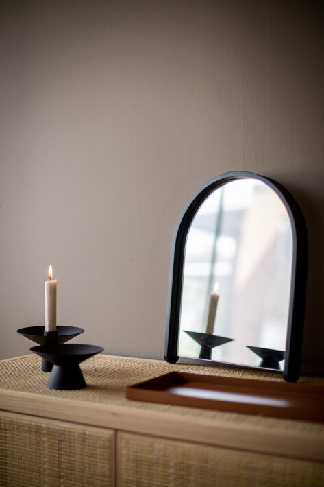 Dizajnové zrkadlo s rámom z čierneho dubového dreva opreté o stenu pri svietniku