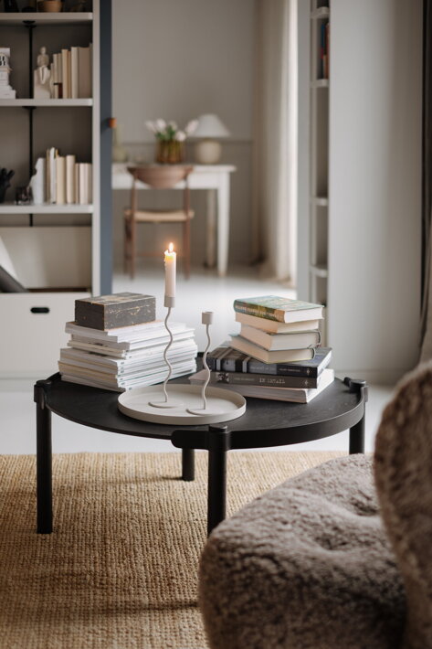 Knihy a časopisy na okrúhlom čiernom stolíku z dubového dreva v obývačke