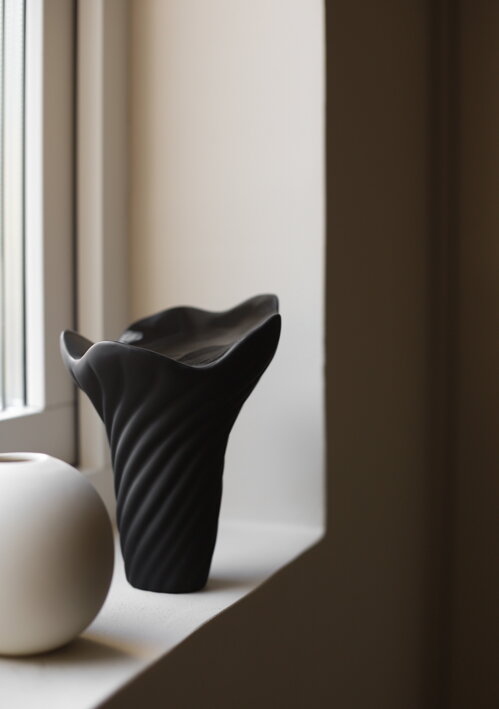 Veľký čierny hríbik z keramiky na parapete pri okne