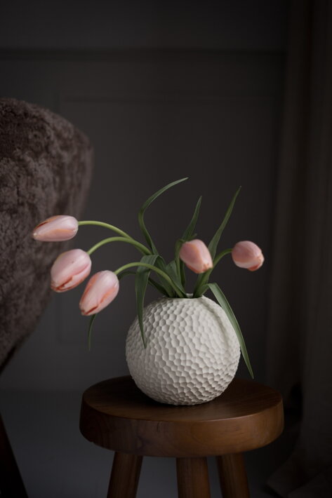 Malá guľatá váza z krémovej keramiky s ružovými tulipánmi na stolíku 