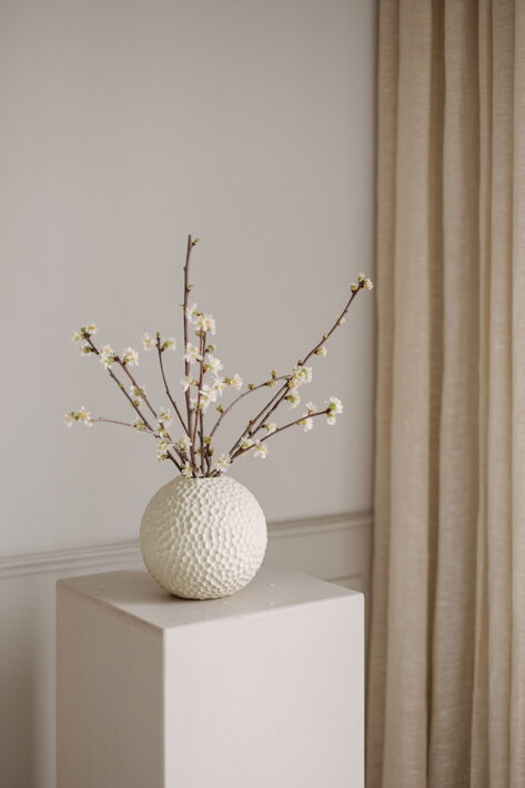 Ručne tvarovaná guľatá váza z krémovej keramiky s jarnými vetvičkami