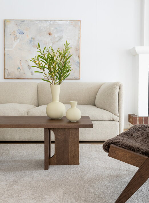 Vysoká dizajnová váza z krémovej keramiky s kyticou kvetov na stolíku v obývačke