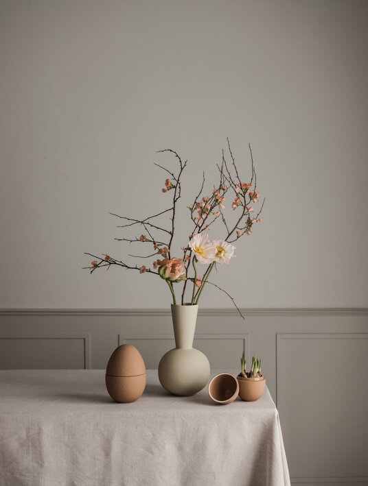 Dekoračné veľkonočné vajíčka pri dizajnovej váze na stole