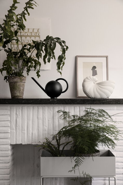 Čierna kovová krhla Orb medzi kvetináčom a vázou v obývačke