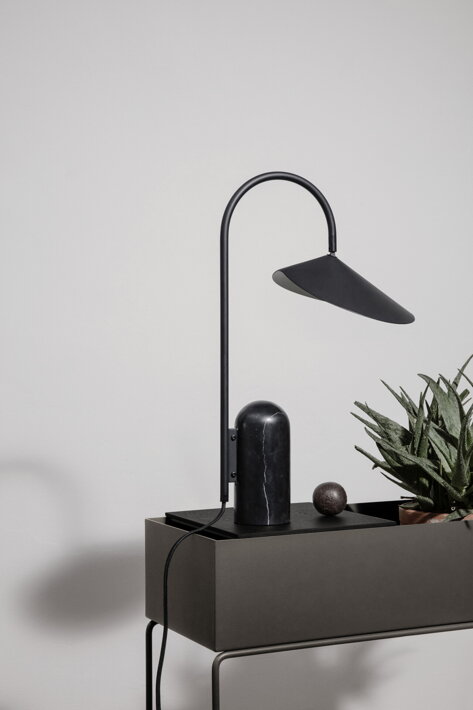 Minimalistická dizajnová lampa na príručnom stolíku s kvetom