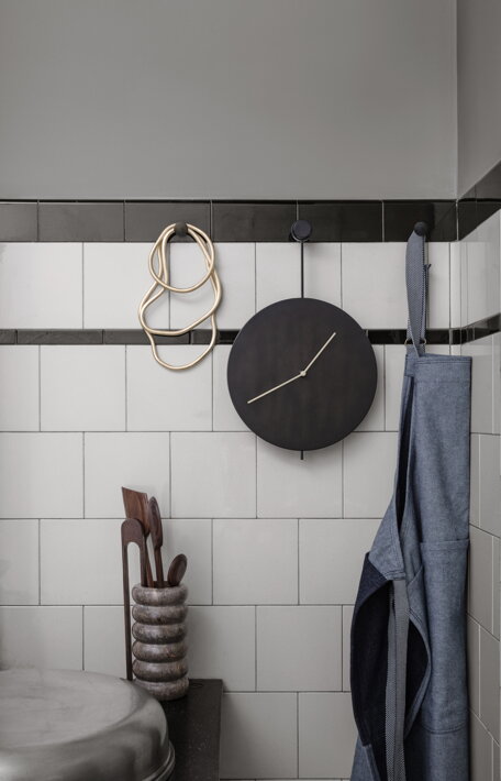 Čierne hodiny s mosadznými ručičkami Trace na stene v kuchyni