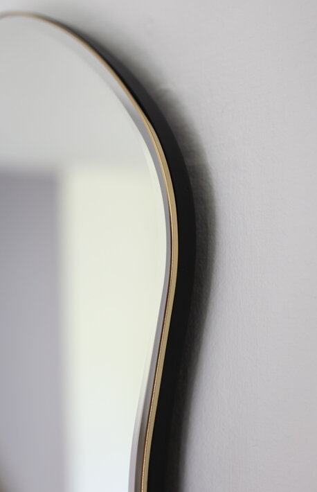 Jemný mosadzný rám na veľkom nástennom zrkadle v nepravidelnom tvare