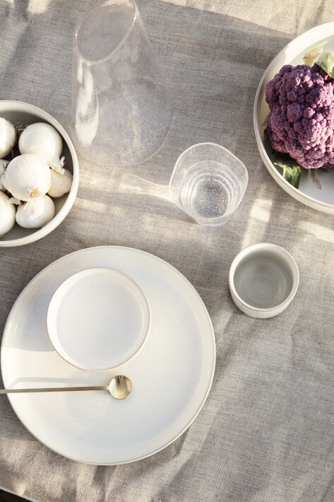 Veľká servírovacia misa z krémovej kameniny na stole s taniermi a pohármi